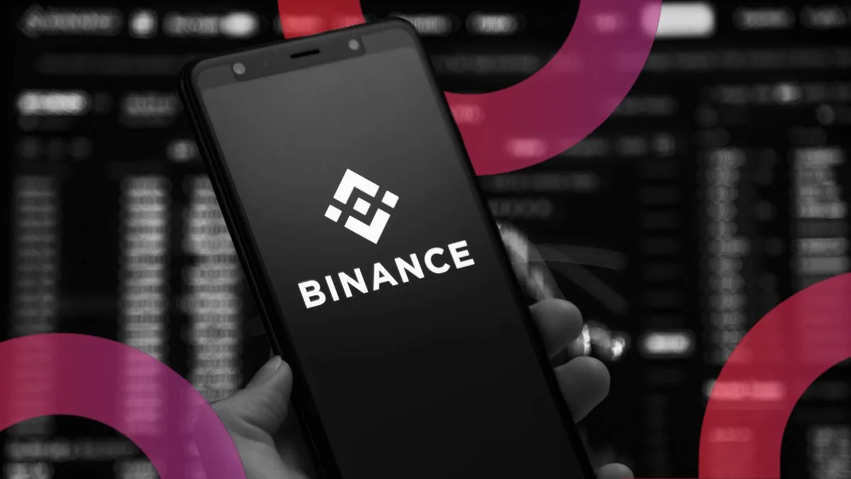 Логотип Binance на тёмном фоне и изображения криптовалютных монет